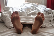 Dirty Bare Feet Of A Sleeping Person Showing Out Of The Blanket
