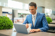 © Minerva Studio - Young businessman drinking a coffee while working at his laptop