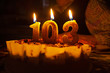 Grandmother's birthday, 103 years. On the table is a birthday cake with candles. Dark background. Horizontal frame.