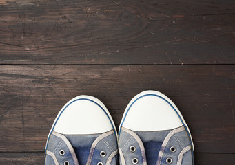 blue men's old  sneakers on a brown wooden surface