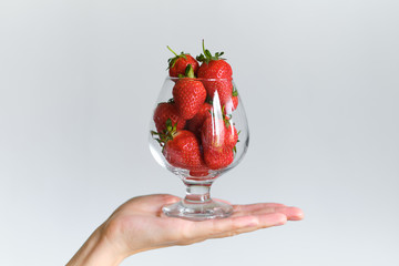 Strawberries in a glass in the hands of a girl. Ripe strawberry closeup. Fresh red juicy berries. Healthy organic sweet fruit. Delicious summer natural dessert. Vitamins diet for woman