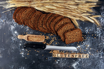 Wall Mural - Sliced rye bread on cutting board. Whole grain rye bread with seeds on table and wooden cubes with words gluten free