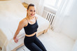© Daria - Beautiful athletic girl, wearing black clothes, pumping press indoors at home in a bright light coloured bedroom on a white bed. Isolated at home. Fitness without gym. Healhty sportive concept