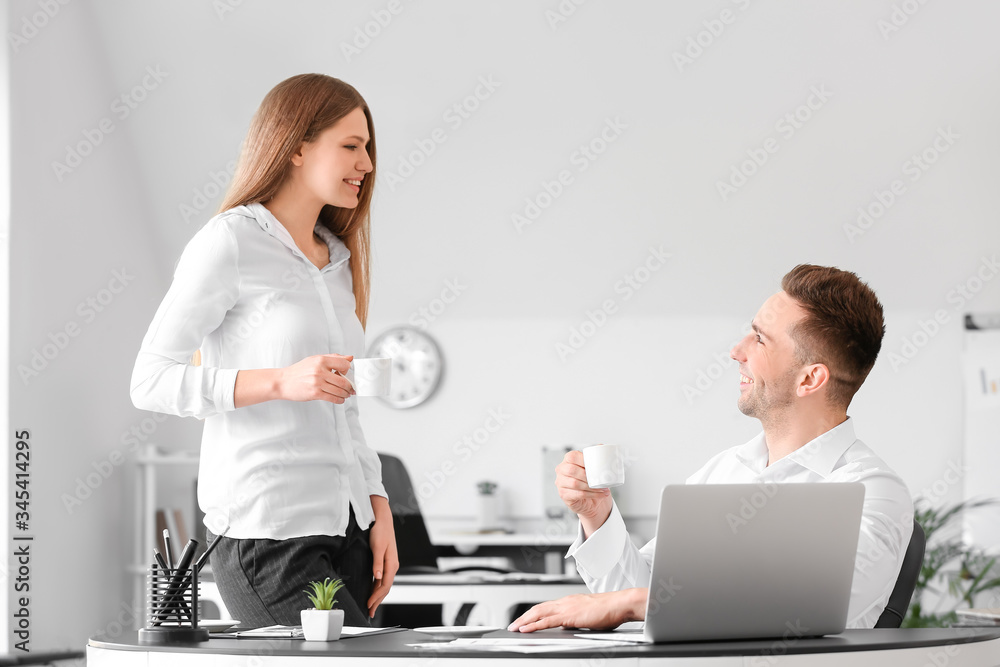 Young colleagues drinking coffee while working in office