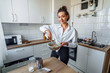 © Daria - Attractive girl preparing dough in a food processor while standing in a bright kitchen. Mixing dough with hand mixer on kitchen table background with cooking ingredients