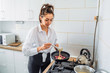 © Daria - Woman pours the dough into a pan to cook homemade fried banana pancakes. Hobby in a beautiful bright kitchen. The economic wife is waiting for her husband from work with delicious tasty food