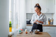 © Daria - DIY home cooking concept. A bright brunette woman sifting the flour for pancakes through a sieve, salting the dough, adding milk. Young woman smiling, loves to cook in a beautiful modern kitchen.