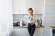 © Daria - Beautiful, attractive, smiling young woman kneading dough with whisk for banana pancakes in steel dishes in a kitchen with white, light interior. Monochrome photo without bright accents