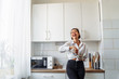 © Daria - Attractive girl preparing dough in a food processor while standing in a bright kitchen. Mixing dough with hand mixer on kitchen table background with cooking ingredients
