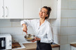 © Daria - Beautiful, attractive, smiling young woman kneading dough with whisk for banana pancakes in steel dishes in a kitchen with white, light interior. Monochrome photo without bright accents