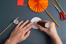 Paper Halloween Jack O'Lantern Step-by-step Instruction. Step 20: Person Applies Glue To A Circle Of White Paper. DIY Halloween Decoration Theme.