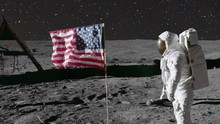 Animation Of An Astronaut In Space Standing On The Moon With American USA Flag , Surrounded By Stars From Moon Landing Apollo Mission. Contains Public Domain Image By NASA