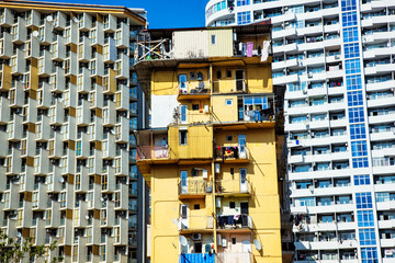 Old poor house on new modern buildings background. Contrast of city architecture concept