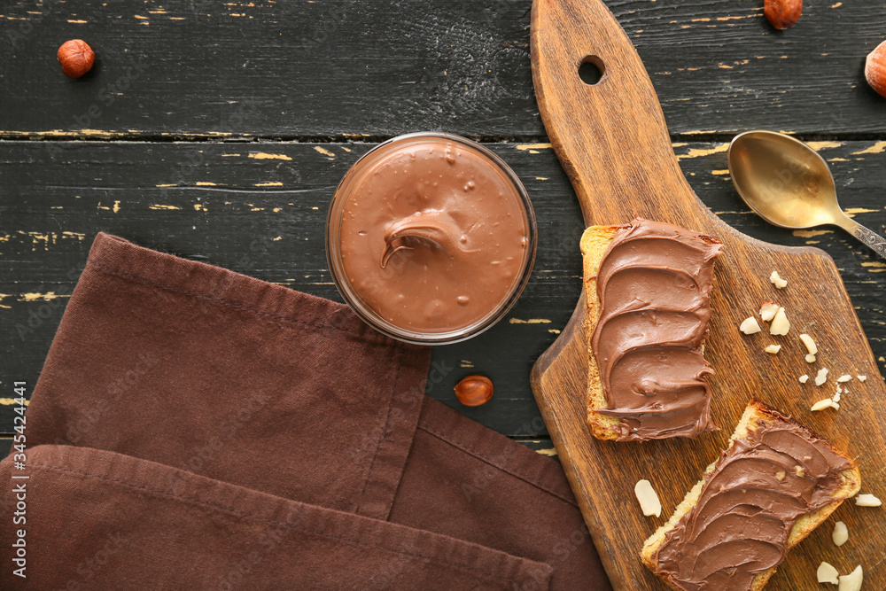Board with fresh bread and chocolate paste on table