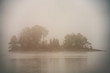 Wyspa na jeziorze spowita gęstą mgłą
