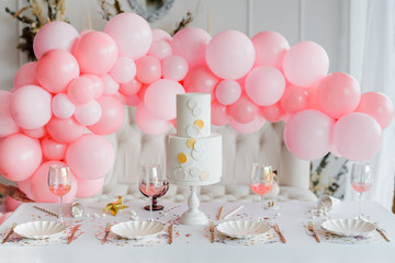 Birthday or wedding table setting in white colors with cocktails in glasses. Baby shower or girl party. Selective focus. Balloon garland