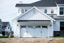 Two Cars Garage Door Painted In White Color In A Typical Single House.