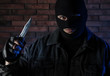© New Africa - Man in mask with knife near brick wall. Dangerous criminal