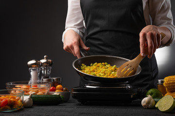 Chef cooks frying vegetables on the background of ingredients. Cooking, tasty and wholesome food. Book of home recipes.