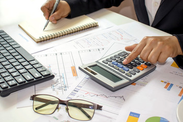 A businesswoman or an accountant who is using a hand press calculator for calculating financial and accounting reports, work concepts and financial accounting.