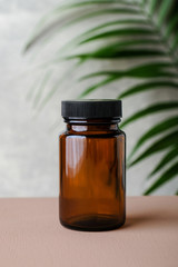 Wall Mural - amber glass supplement bottle and tropical green leaf. medical package for pills, capsule, drugs. he