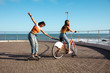 © Wavebreak Media - Side view of friends having fun with a skate and a bike