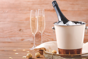 Bucket with ice and champagne on wooden background