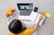 © weedezign - Asian female student video conference with teacher and friends using e-learing app on laptop computer at home.woman lying down on carpet.new normal learning online lifestyle