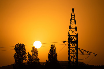 silhouette of an energy tower at dawn with the sun in the background. concept of solar, ecological and renewable energy.