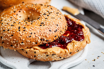 Bagels with peanut butter and berry jam on white board. Vegan food concept.