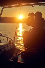 Wall Mural - Sailor steering sailing boat with a rudder in dawn / twilight time on tje open sea.