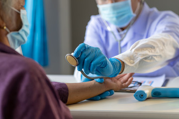 Asian doctor use stethoscope listening lung of patient, elderly health check up , they wear surgical mask the aging female patient that is at risk for infection corona virus [covid-19].