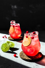 Wall Mural - Cranberry tonic with lime in beautiful glasses, grey background, direct natural light