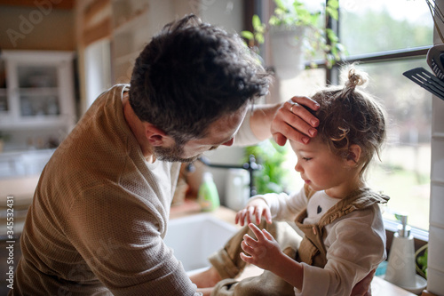 Cuadros en Lienzo Father checking forehead of sick toddler daughter indoors at home
