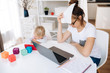 © Kateryna - Tired young caucasian woman manage household finances she counting home expenses and paying bills online, and her little adorable daughter is sitting nearby and watching a cartoon on a telephone