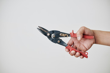 Builder holding professional sharp metal shears with orange handlers