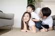 © sattahipbeach - Attractive Asian family happy hug and kiss smile together lying down on carpet floor in living room at home