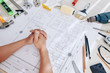 © DragonImages - Construction engineer sitting at desk with working tools and blueprint of house
