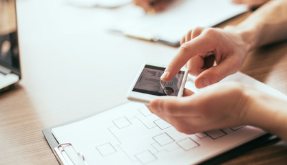 close up. employee using their smartphone to work with new data.