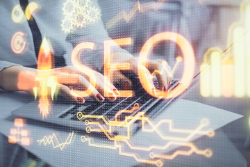 Double exposure of woman hands working on computer and seo hologram drawing. internet search concept.