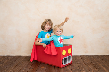 Superheroes children playing in cardboard box