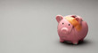 Broken piggy bank with band-aid on gray background