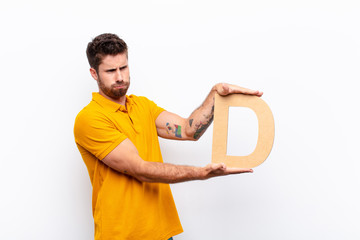 Wall Mural - young handsome man angry, anger, disagreement, holding the letter D of the alphabet to form a word or a sentence.