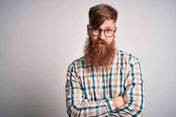 Sticker - Handsome Irish redhead man with beard wearing glasses and hipster shirt skeptic and nervous, disapproving expression on face with crossed arms. Negative person.