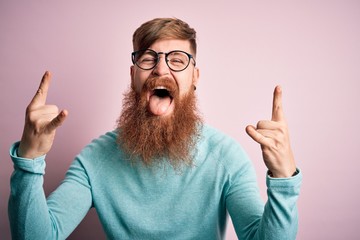 Poster - handsome irish redhead man with beard wearing glasses over pink isolated background shouting with cr