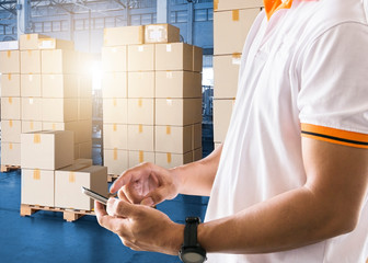 Wall Mural - warehouse shipper hand holding smartphone with contacts to a customer, interior of warehouse shipping package boxes, business logistics shipment transport, cargo export