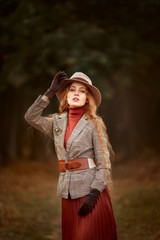 Wall Mural - Beautiful long-haired blonde young woman in English style portrait in autumn forest