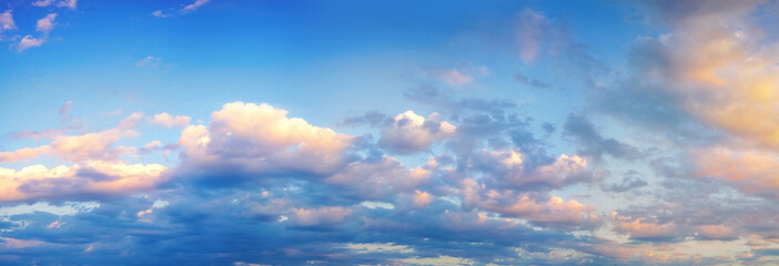 Wall Mural - Beautiful colorful panorama of blue sky with white and pink scattered cumulus clouds during summer sunrise or sunset. Panoramic view.