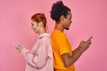 beautiful, pretty, cute red hair woman and handsome dark skinned man standing back to back and writi