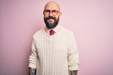 Wall Mural - Handsome bald man with beard and tattoo wearing glasses and sweater over pink background with a happy and cool smile on face. Lucky person.